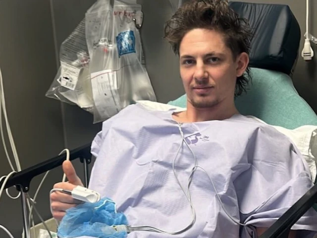 Stecher poses in a hospital bed while his Oilers teammates continue on